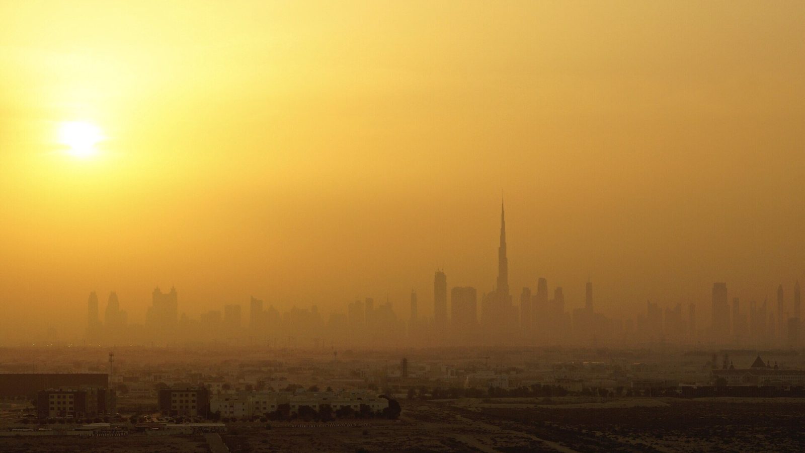 شمس صيف دبي الحارقة فوق الأفق في يوم مغبر